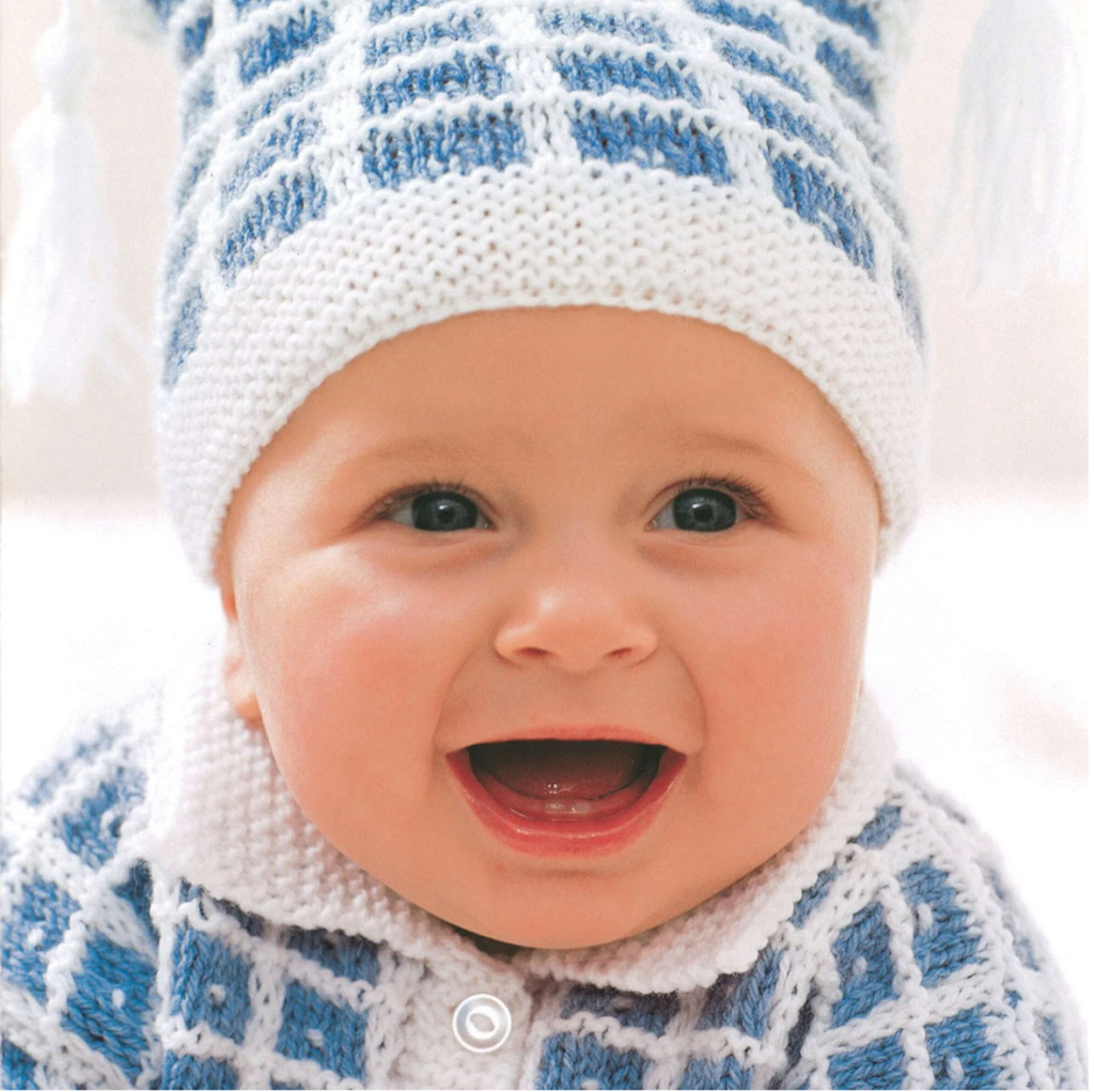 baby sitting in winter knitted hat and cardigan